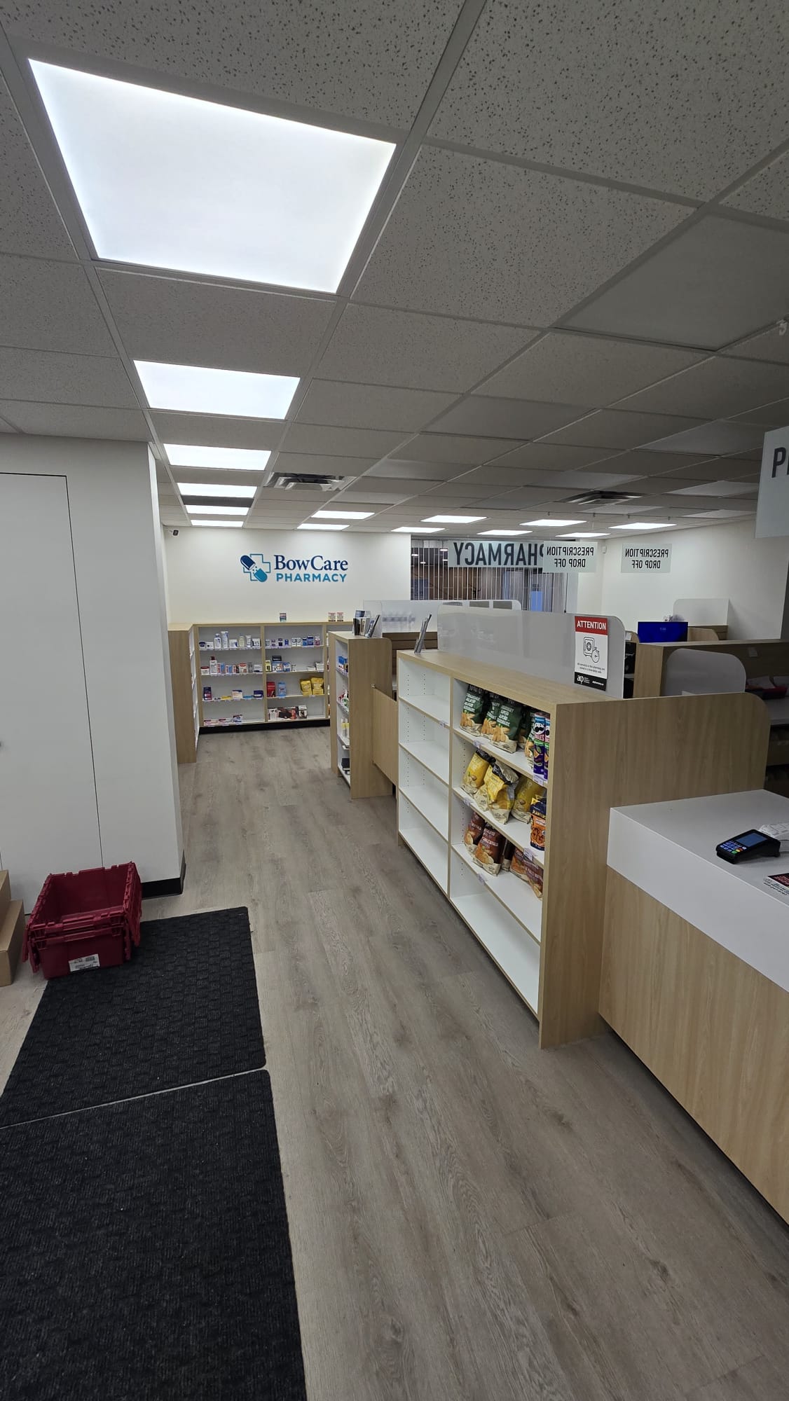 Bow Care Pharmacy dispensary aisle with shelving and prescription drop-off counter