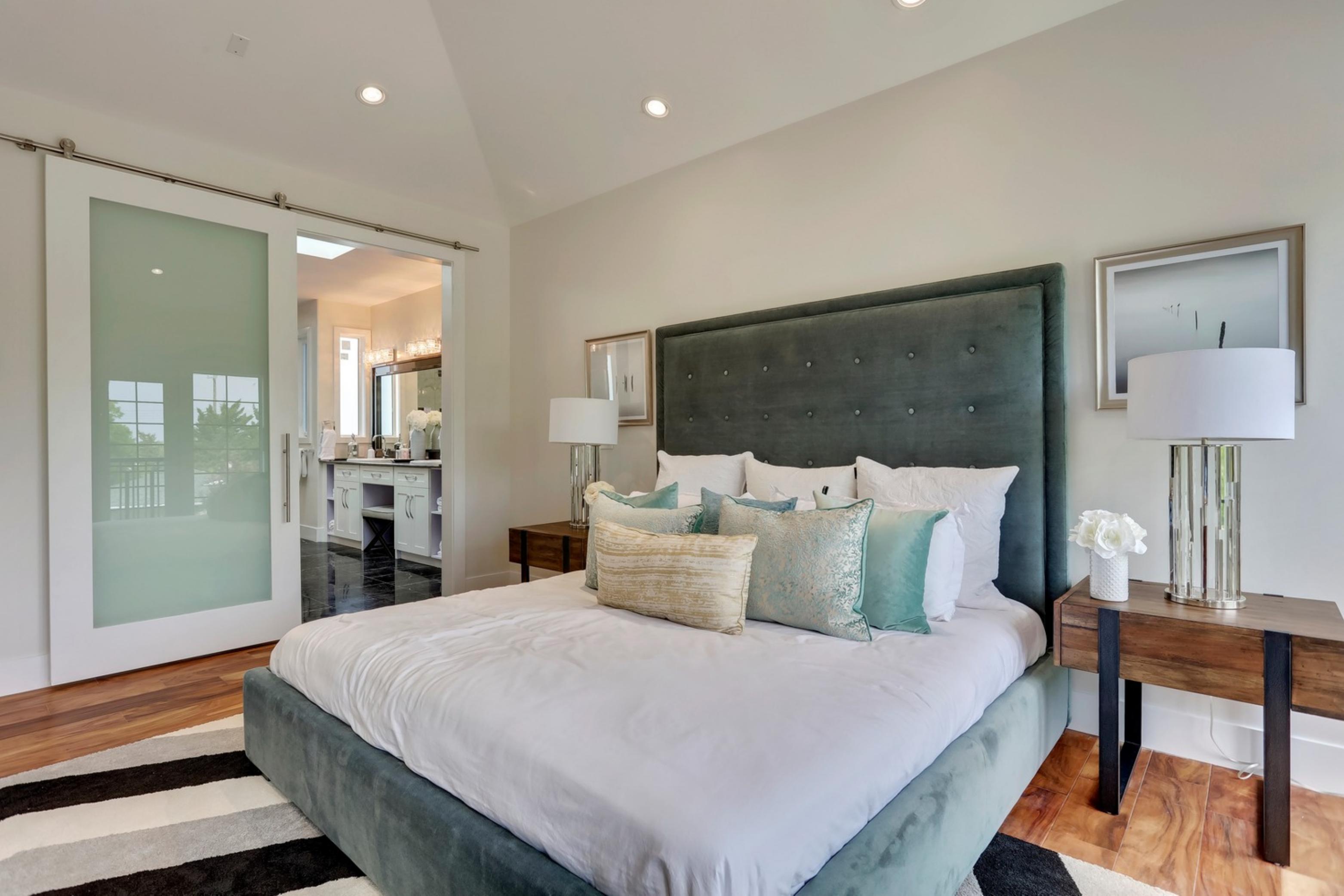 Killanery Custom Residence primary bedroom with tufted headboard and barn door to ensuite